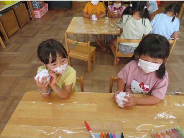 4歳は新聞紙を丸め、包むように白い紙を丸めていきます。