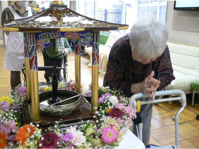 仏像に甘茶を灌（そそ）いで心を込めてお祈りしています。