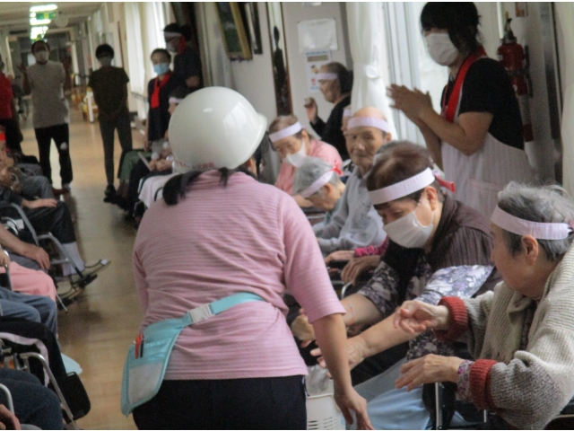 ヘルメットを被った職員が利用者の前に籠を持って移動しました。