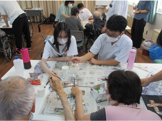 広告をちぎる人、のりで貼る人。世代を超えて共同作業。