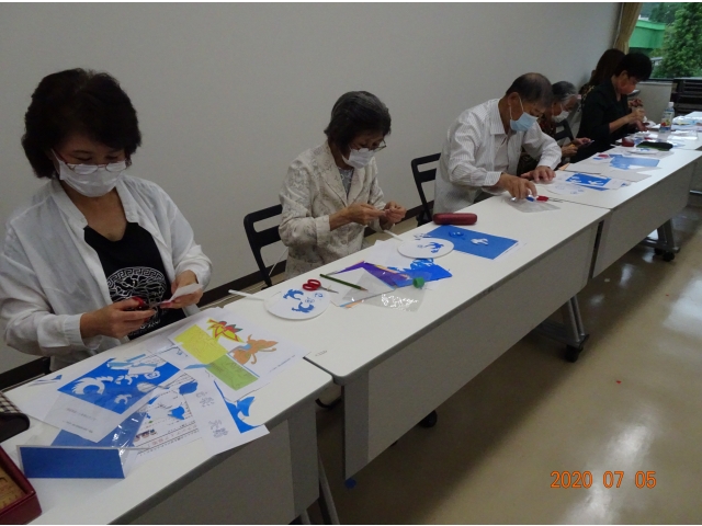 団扇に貼る絵を切っています。