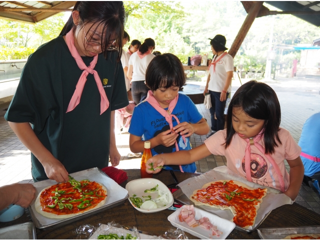 野外炊飯　ピザ作りピザソースを塗って野菜、チーズをトッピングします